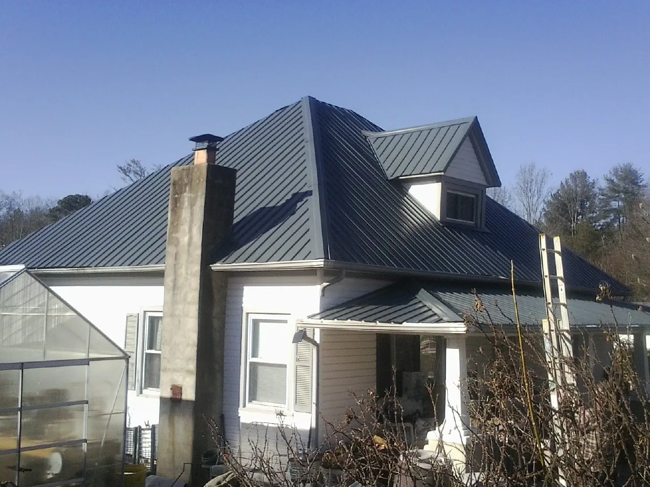 Dark blue standing seam metal roof on a white farmhouse with dormer — Slate & Tile Roof Repair by Roofing Brothers in Oakesdale