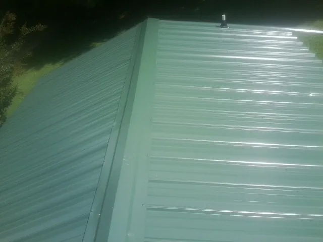 New green metal panels meeting at the ridge of a roof — Flat Roof Repair work by our crew in Oakesdale