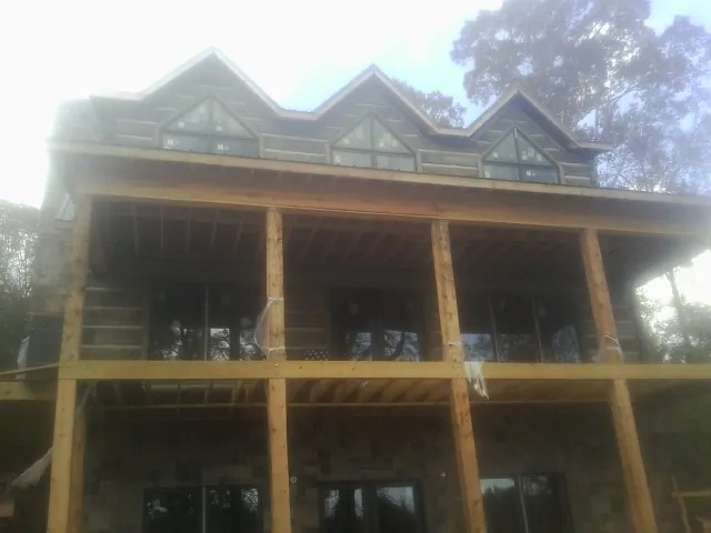 Dormers and porch framing on a large log home under construction — Roof Coating work by our crew in Oakesdale