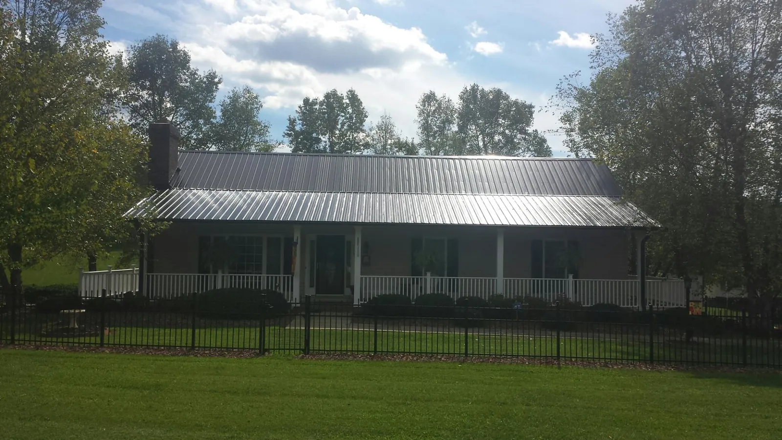 Gray metal roof on a brick ranch with a full width front porch — Gutter Guard Installation work by our crew in Oakesdale