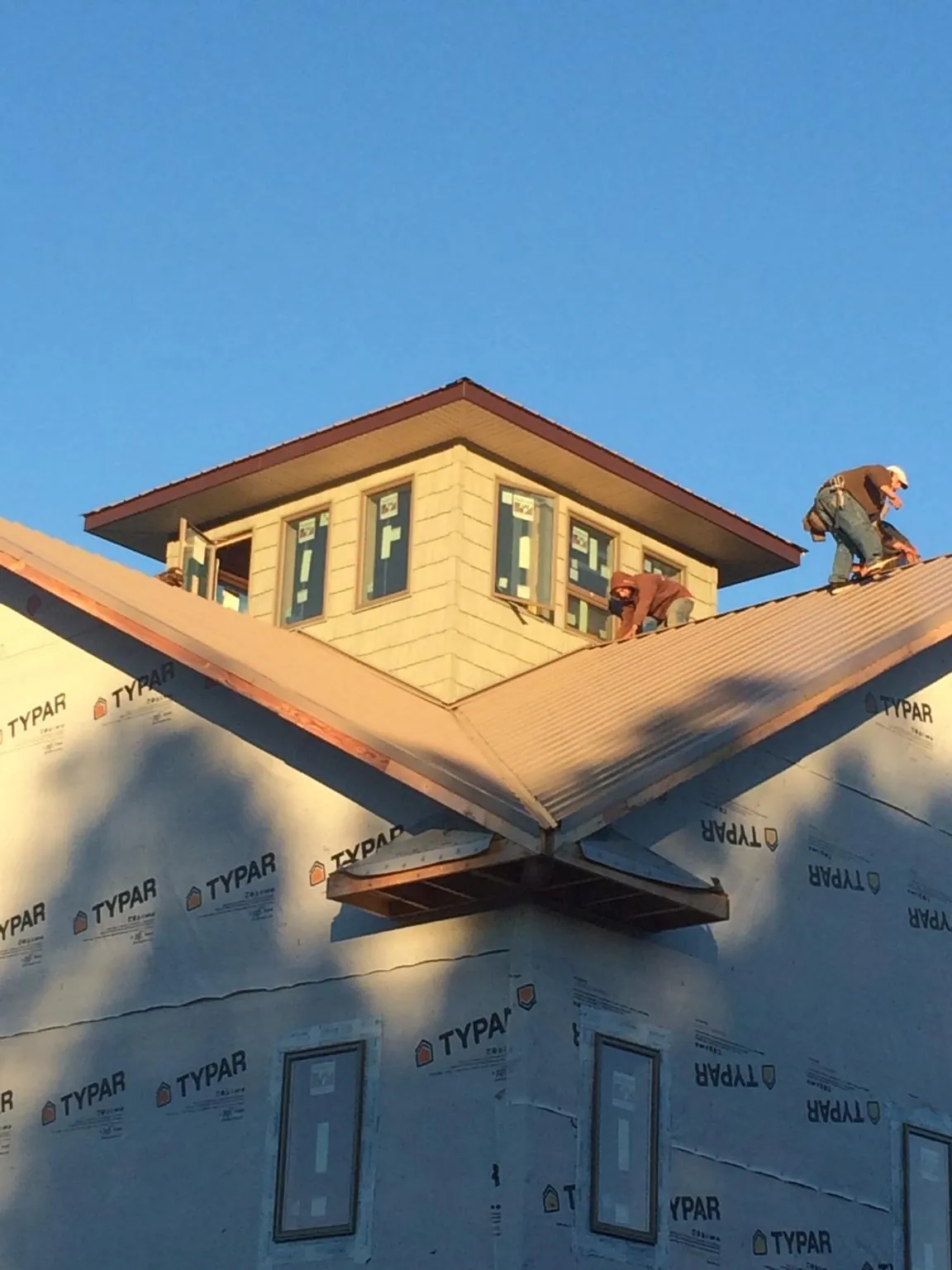 Roofers working around a rooftop cupola on a new metal roof at sunset — Roof Waterproofing in Oakesdale by Roofing Brothers